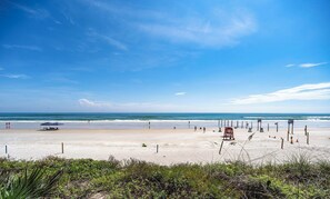 Une plage avec un poste de surveillance pour les sauveteurs, des parasols et des chaises de plage.