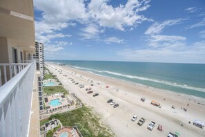 Vue sur la plage depuis un balcon donnant sur une piscine et un espace de détente.