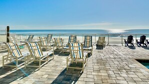 A beachside lounge with rows of striped lounge chairs facing the ocean, a pool, and a clear view of the beach. - #1005 Sanibel - Direct Oceanfront SE Corner Unit (Daytona Beach Shores)
