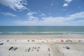 A beach with a parking area and a view of the ocean.