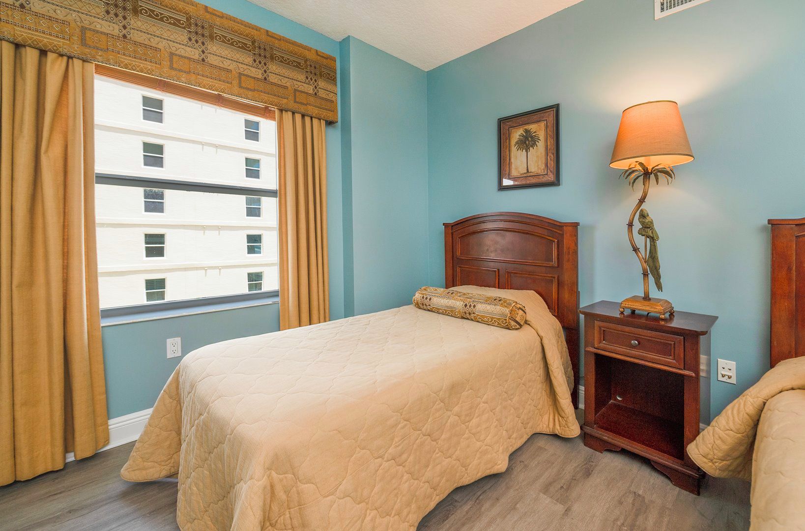 Une chambre d’hôtel avec un lit, une table de chevet, une lampe et une fenêtre avec des rideaux.