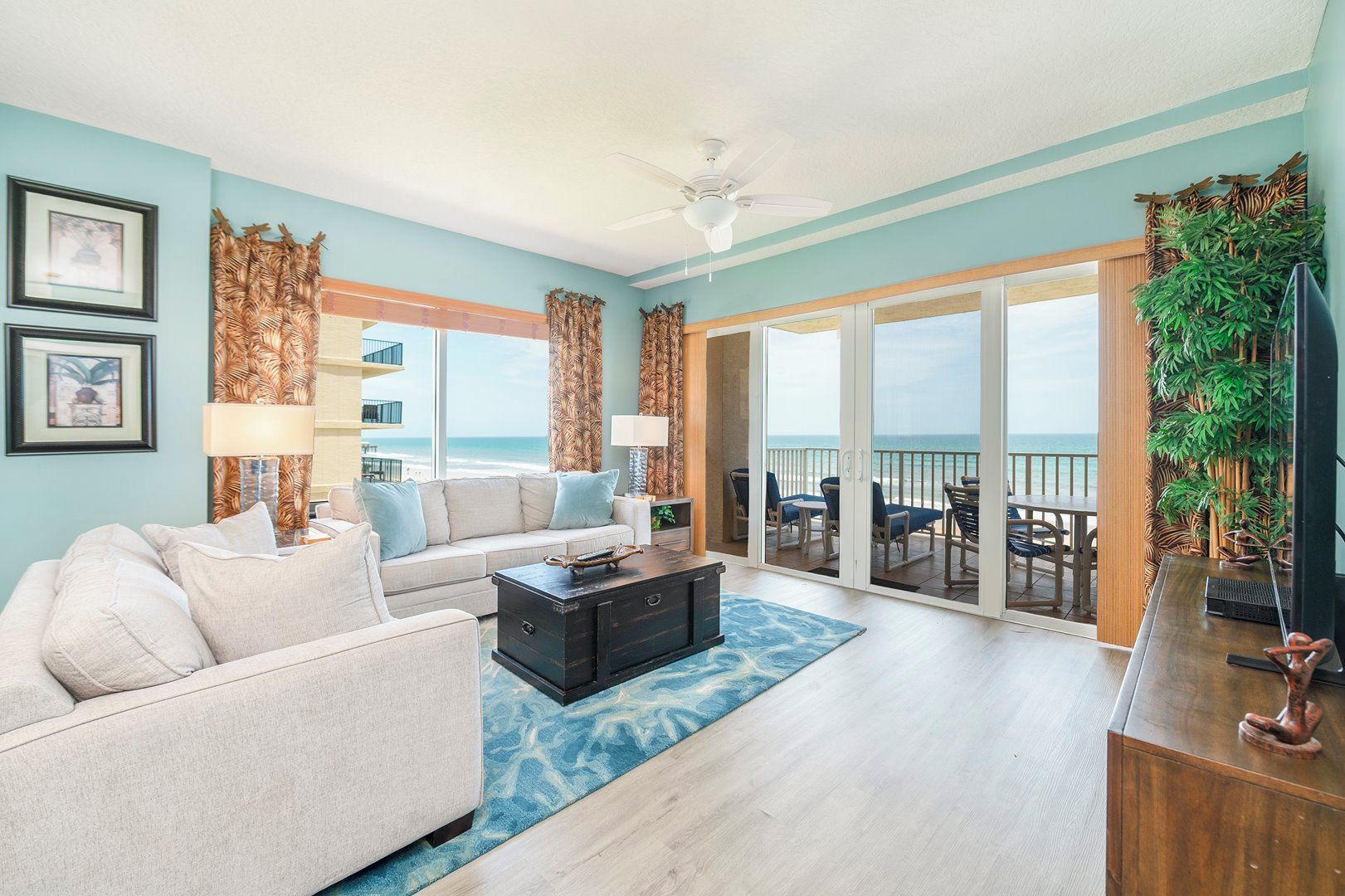 A spacious living room with a sofa, coffee table, and a view of the ocean through large sliding doors.