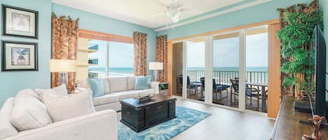 A spacious living room with a sofa, coffee table, and a view of the ocean through large sliding doors.