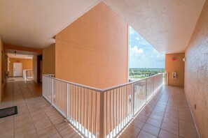 A corridor with a balcony, white railing, and a view of the landscape. - Sanibel Condo #302 3/3 Direct Oceanfront NE Corner (Daytona Beach Shores)