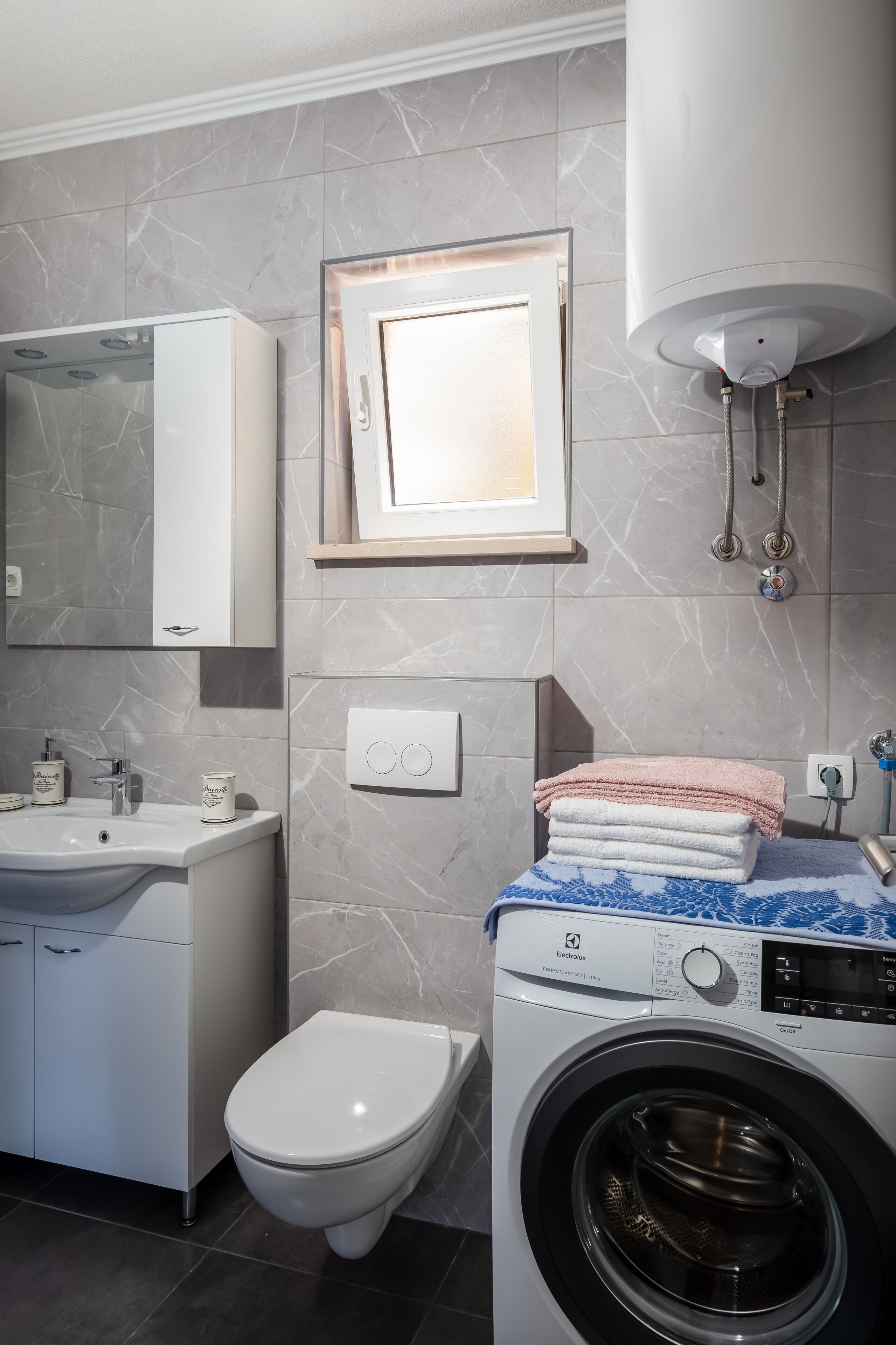 Et moderne badeværelse med toilet, vask og vaskemaskine.