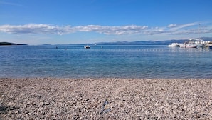 A pebbled beach with boats docked in the background. - Luxury 6-BR Waterfront Villa with Infinity Pool and direct access to a pebble beach (Supetar)