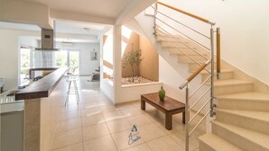 A modern kitchen with a bar area, a staircase with wooden handrails, and a small table with a vase. - Luxury 6-BR Waterfront Villa with Infinity Pool and direct access to a pebble beach (Supetar)