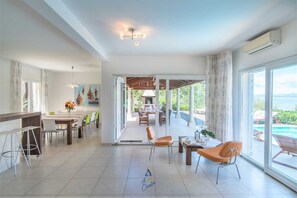 Een ruime woonkamer met een eettafel, stoelen en uitzicht op de omgeving.