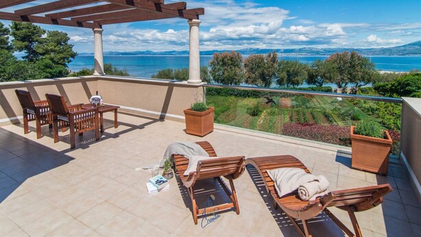 A terrace with wooden furniture, a pergola, and a view of the sea and mountains. - Luxury 6-BR Waterfront Villa with Infinity Pool and direct access to a pebble beach (Supetar)