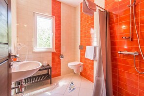 Een badkamer met een witte wastafel, toilet en douche.