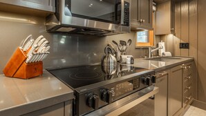 Une cuisine moderne équipée d’appareils électroménagers en acier inoxydable, notamment un four à micro-ondes, une cuisinière et un four. On y trouve également un bloc à couteaux sur le plan de travail et une bouilloire.