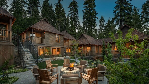 Un complexe hôtelier de style rustique, composé de plusieurs bâtiments en bois, doté d’espaces de détente en plein air et d’un foyer.