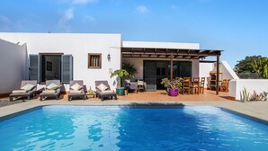A swimming pool with lounge chairs and a covered seating area.