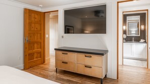Un dormitorio con armario de madera, cama y baño con espejo y lavamanos.