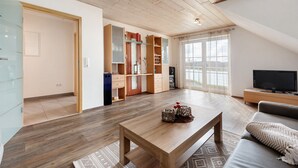 A modern living room with a wooden coffee table, a sofa, and a TV. - Cozy Top-Floor Apartment "Vogelsang" with Mountain View, Wi-Fi & Balcony (Herdwangen-Schönach)