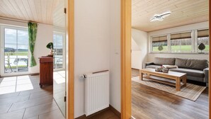A modern living room with a wooden floor, a white radiator, a wooden coffee table, and a grey sofa. - Cozy Top-Floor Apartment "Vogelsang" with Mountain View, Wi-Fi & Balcony (Herdwangen-Schönach)