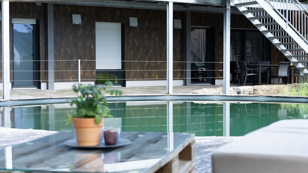 Un bâtiment moderne doté d’une piscine, d’un espace extérieur aménagé et d’un escalier.