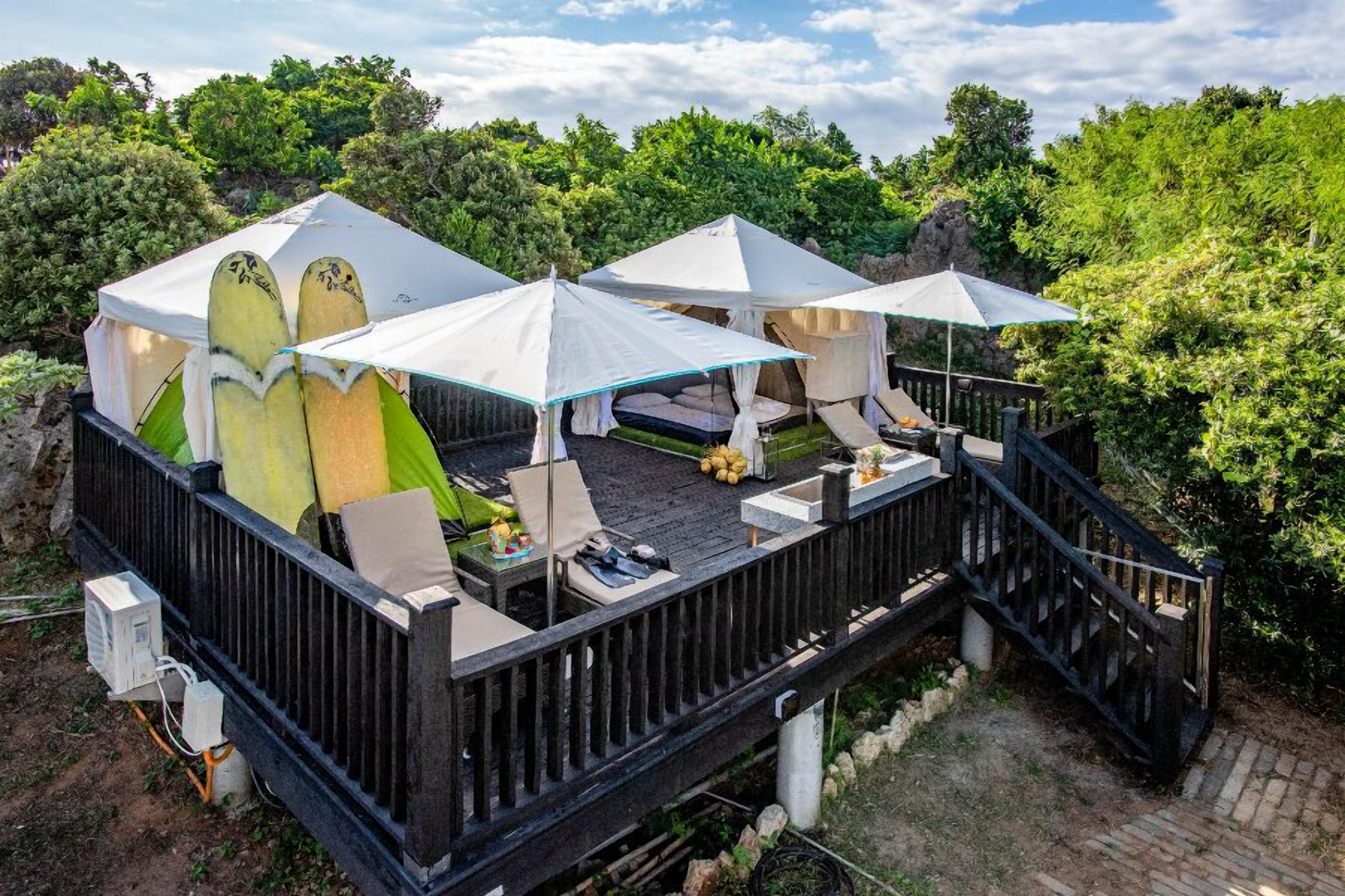 A deck with two tents, a table, and chairs.