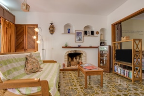 A cozy living room with a sofa, fireplace, bookshelf, and a television.