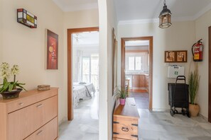 A hallway with a wooden cabinet, a potted plant, a fire extinguisher, and a fire hose.