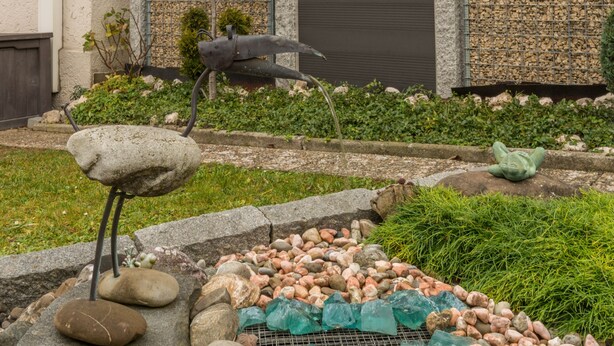 A garden with a bird sculpture, a stone frog, and a pile of rocks. - Holiday Apartment Kramer with Wi-Fi, Terrace & Shared Garden (Überlingen)