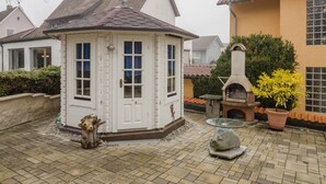 A white building with a tiled roof, a stone chimney, and a potted plant. - Holiday Apartment Kramer with Wi-Fi, Terrace & Shared Garden (Überlingen)