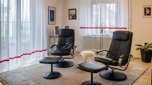 A room with two black leather chairs, a small stool, a radiator, and a potted plant. - Holiday Apartment Kramer with Wi-Fi, Terrace & Shared Garden (Überlingen)