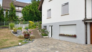 A residential building with a paved driveway, a wooden fence, and potted plants. - Holiday Apartment Kramer with Wi-Fi, Terrace & Shared Garden (Überlingen)