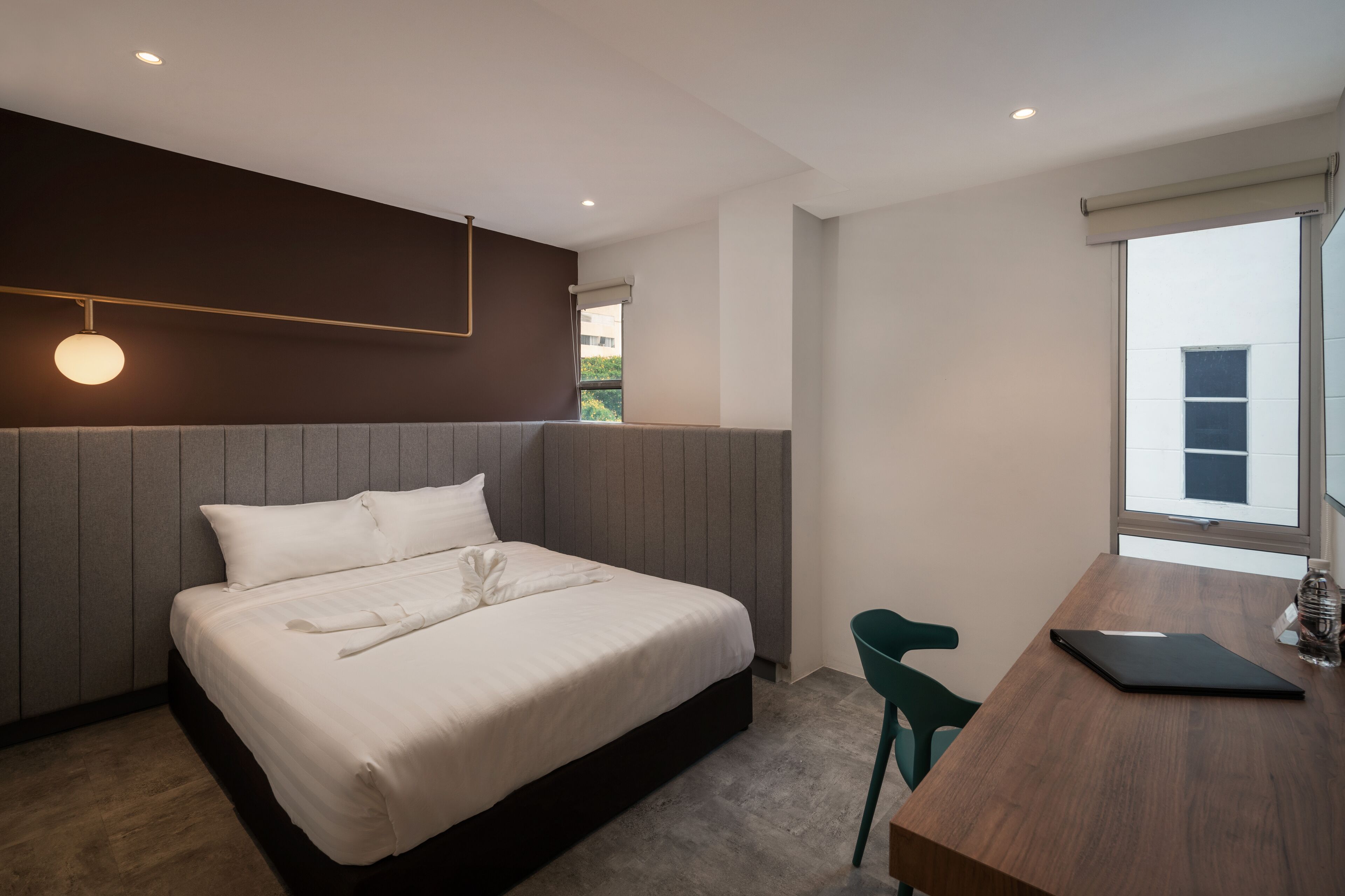 A modern bedroom with a large bed, a wooden desk, and a view of the outside.
