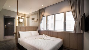 Une chambre d’hôtel moderne dotée d’un grand lit, d’une douche à l’italienne, d’une vue par la fenêtre et d’un téléviseur à écran plat fixé au mur.