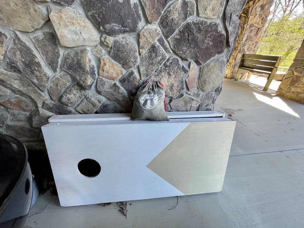 A stone wall with a bench and a white storage box with a hole.
