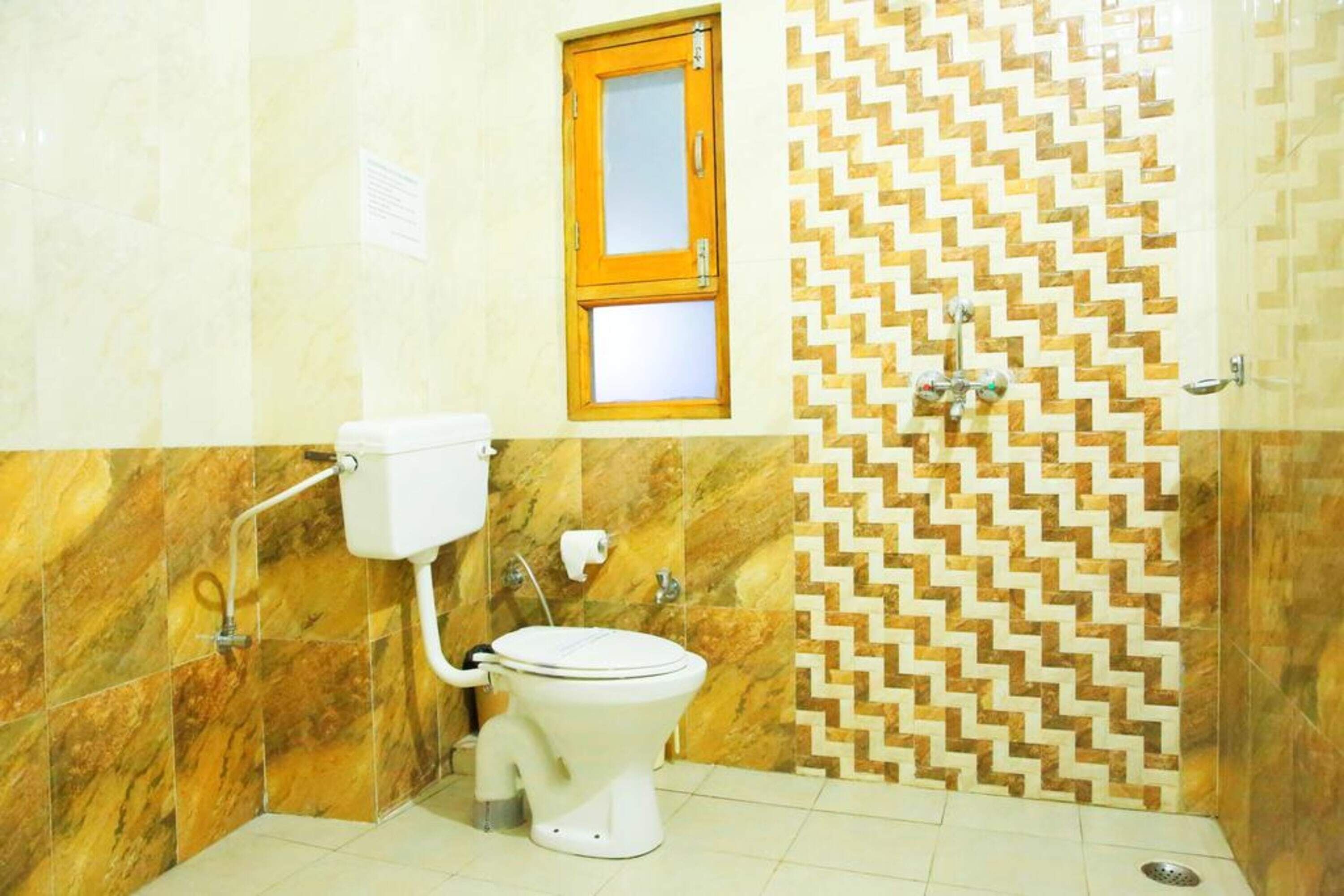 A bathroom with a toilet, a window, and a shower area.