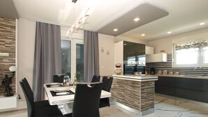 A modern kitchen with a central island, a dining area with a glass table, and a kitchen island with a built-in sink.
