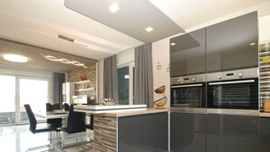 A modern kitchen with dark cabinets, a marble countertop, and two built-in ovens.