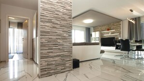 A modern living room with a sofa, a dining area with a table and chairs, and a kitchen in the background.