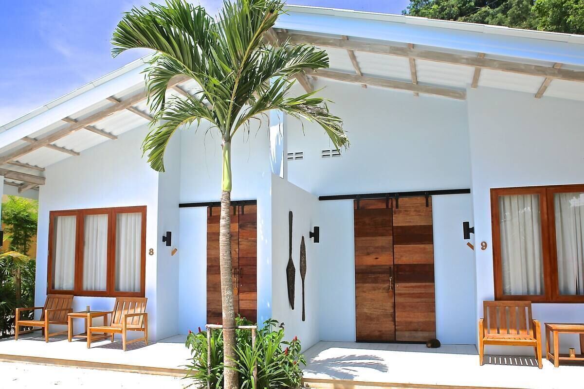 A modern building with a covered porch, wooden doors, and a palm tree.