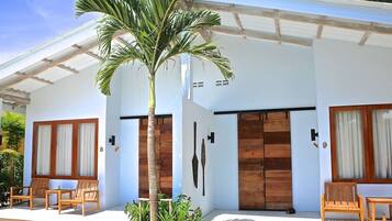 A modern building with a covered porch, wooden doors, and a palm tree.