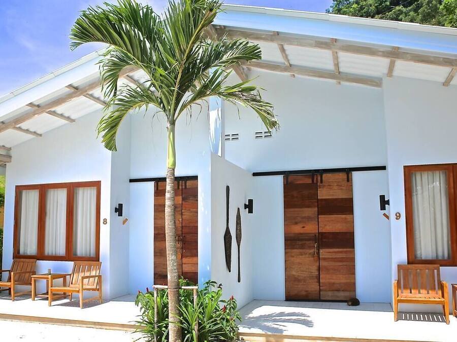 A modern building with a covered porch, wooden doors, and a palm tree.