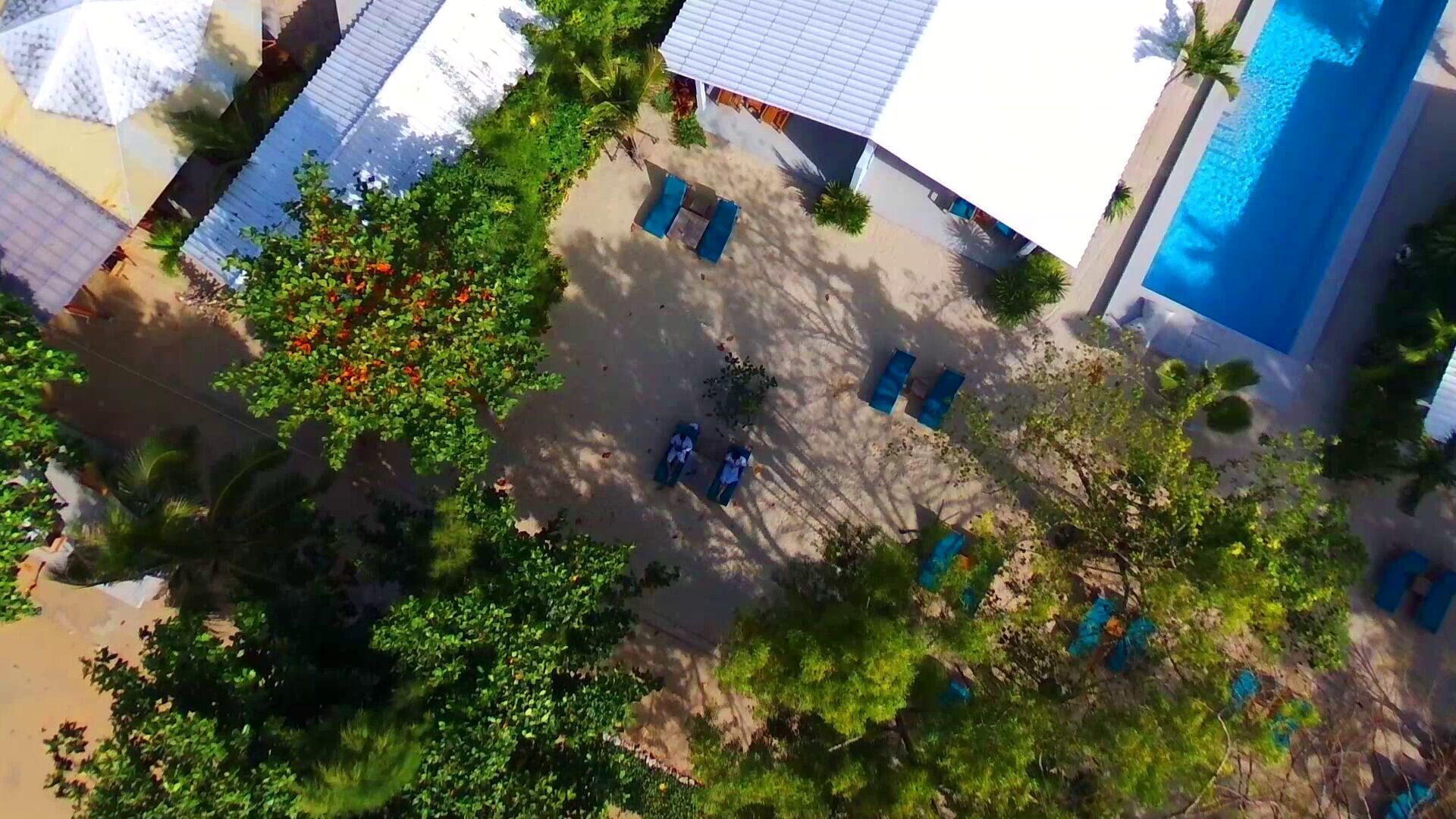 An aerial view of a resort with multiple buildings, a swimming pool, and lush greenery.