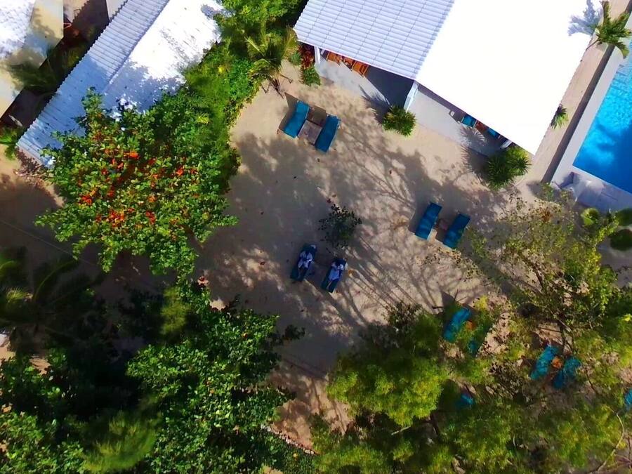 An aerial view of a resort with multiple buildings, a swimming pool, and lush greenery.