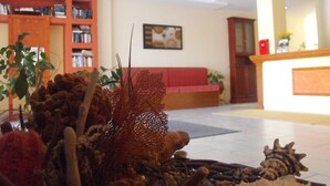 Um lobby com uma mesa de recepção, um sofá vermelho e uma estante cheia de livros.