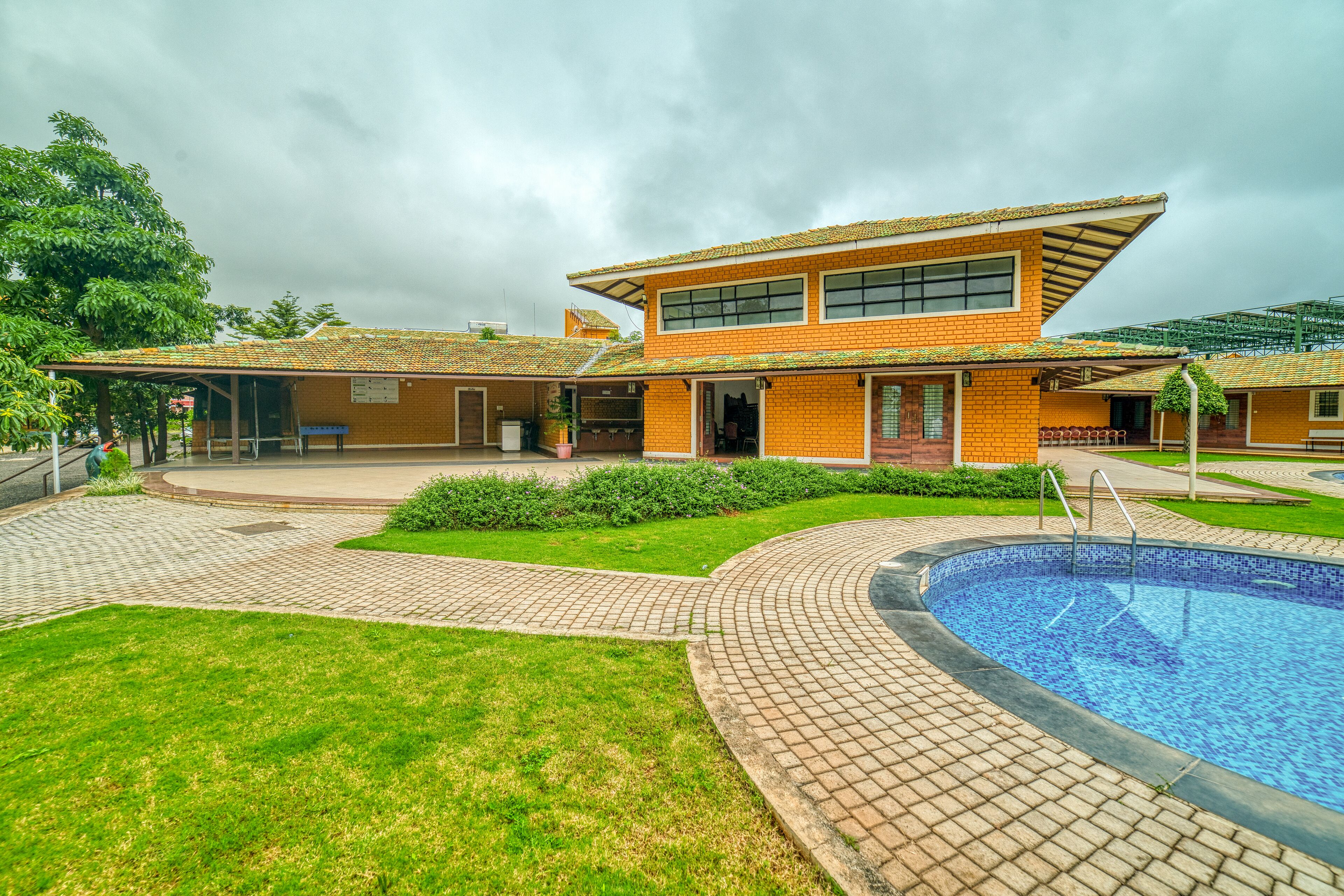 Un edificio moderno con piscina, un patio cubierto y un césped cuidado.