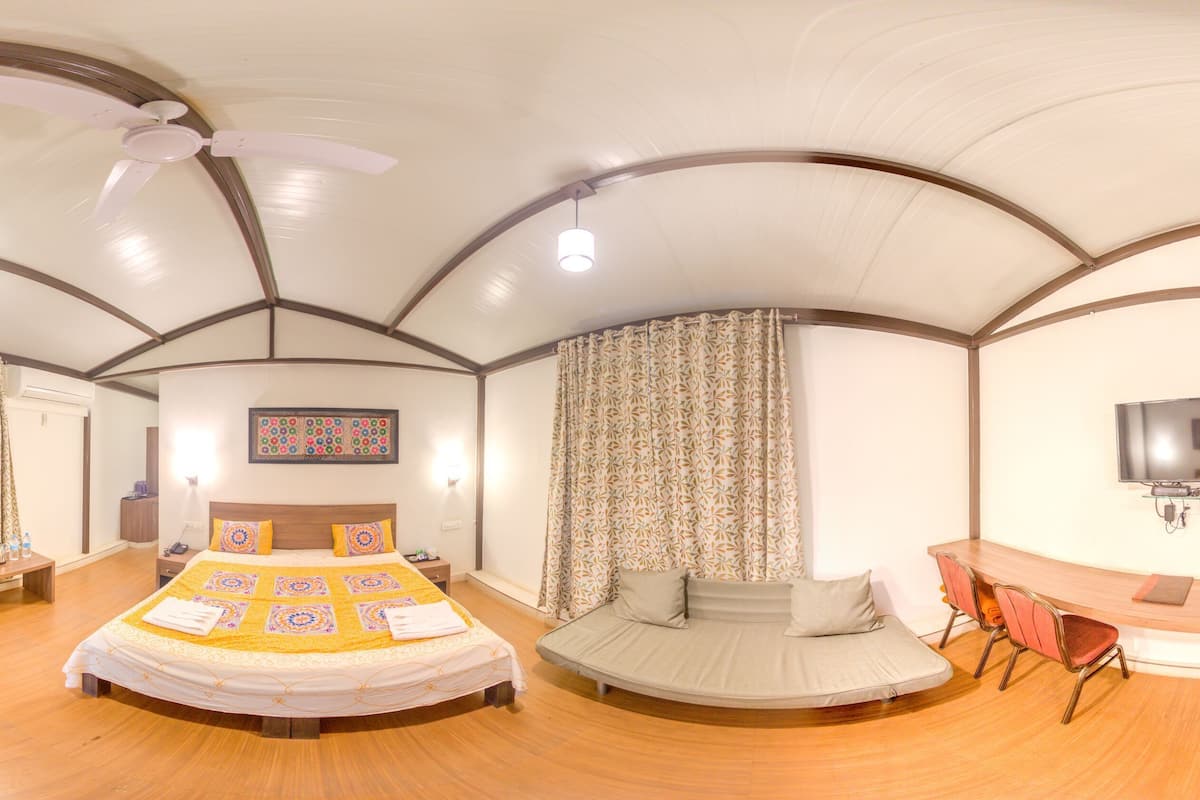 Ein geräumiges Zimmer mit einem großen Bett, einem Schlafsofa, einem Sessel und einem Schreibtisch.