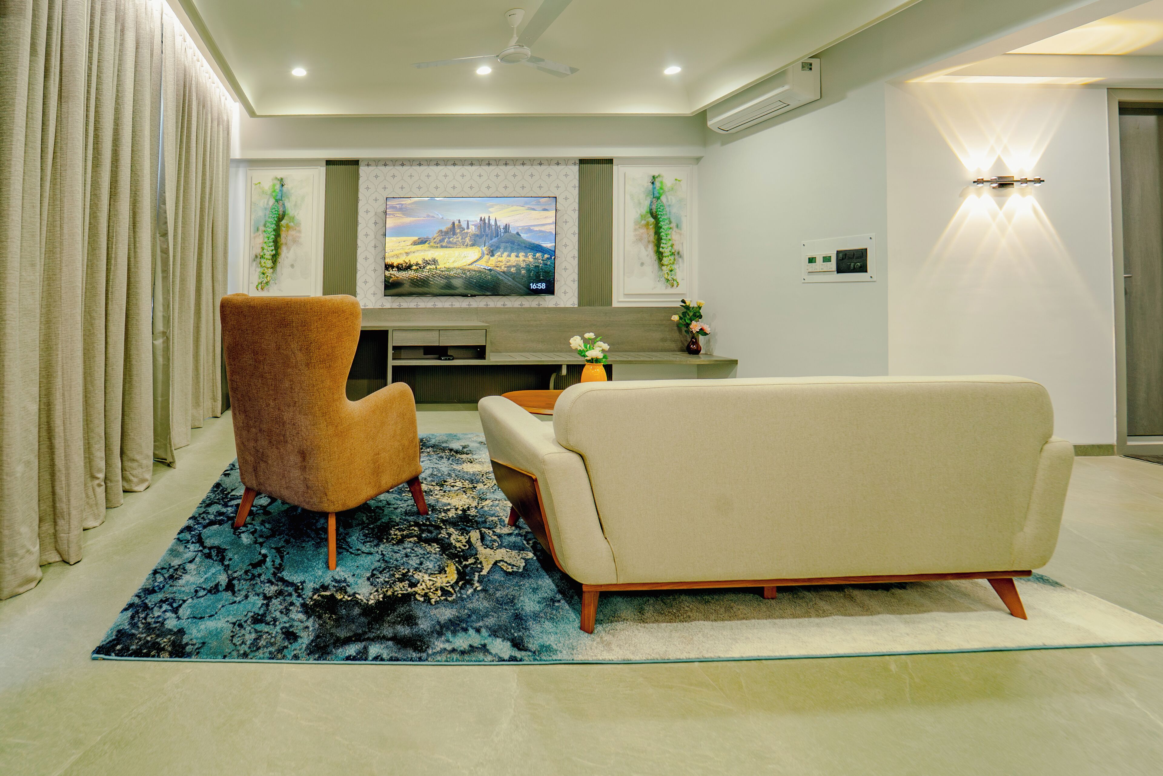 A modern living room with a flat-screen TV, two sofas, a coffee table, and a patterned rug.
