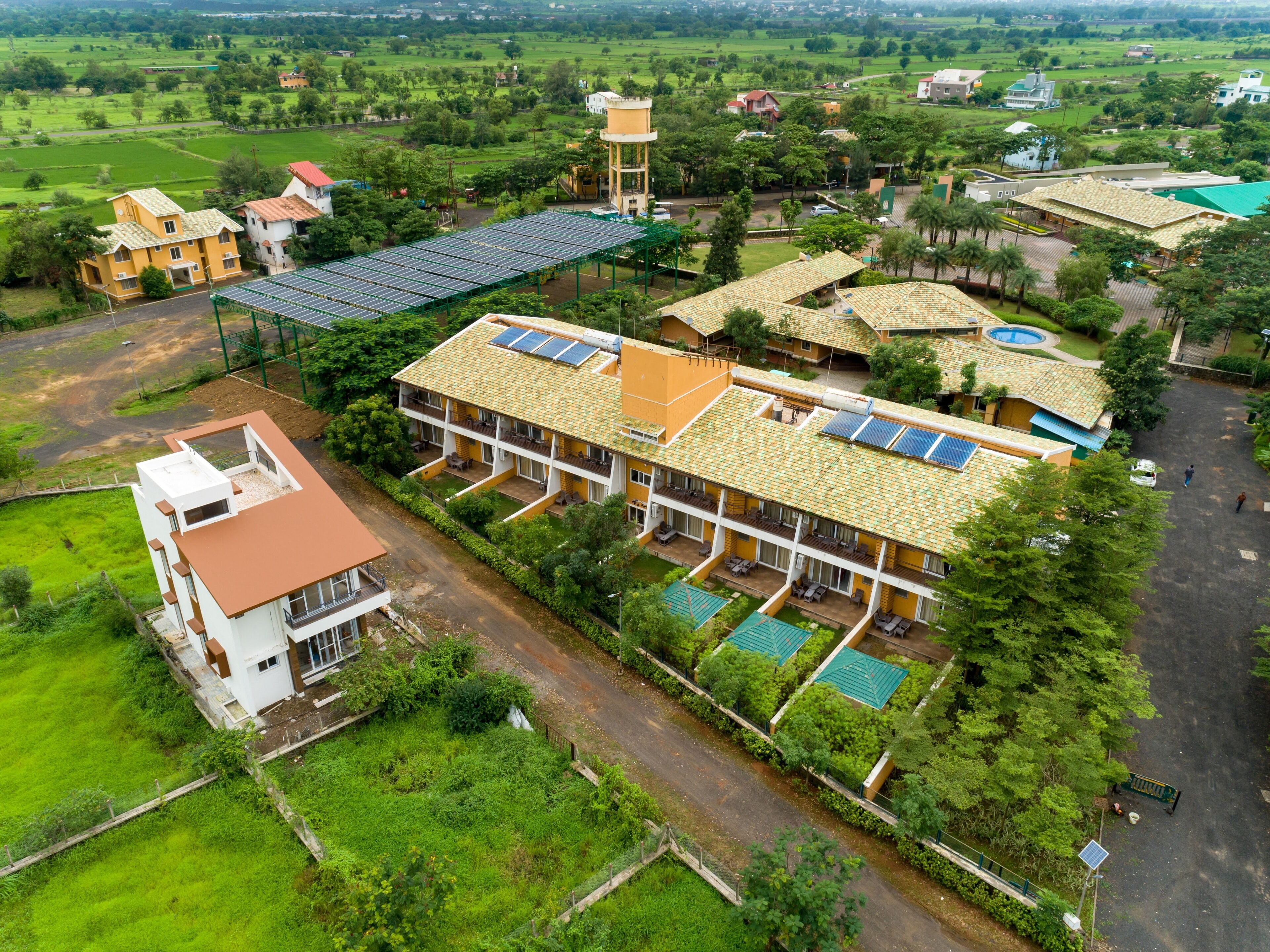 A large building with multiple floors, solar panels on the roof, and a swimming pool.