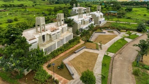Ein modernes Hotel mit mehreren Stockwerken, umgeben von üppiger Vegetation und hügeliger Landschaft.
