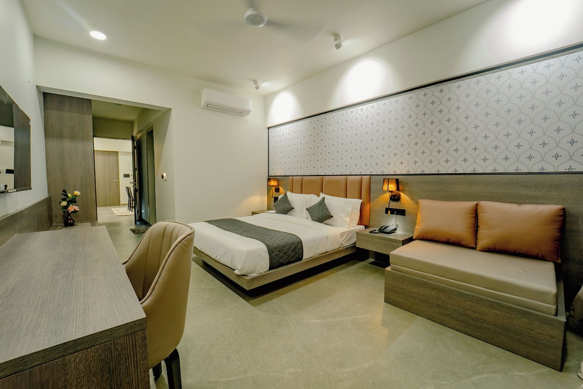 Ein modernes Hotelzimmer mit Bett, Nachttisch, Sofa und Schreibtisch.
