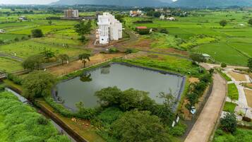 A large, rectangular water body surrounded by lush greenery and a few buildings, including a prominent white structure.