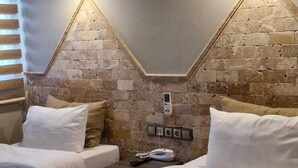 A hotel room with two beds, a brick accent wall, and a wall-mounted phone. - Royal Park Hotel Corlu (Corlu)
