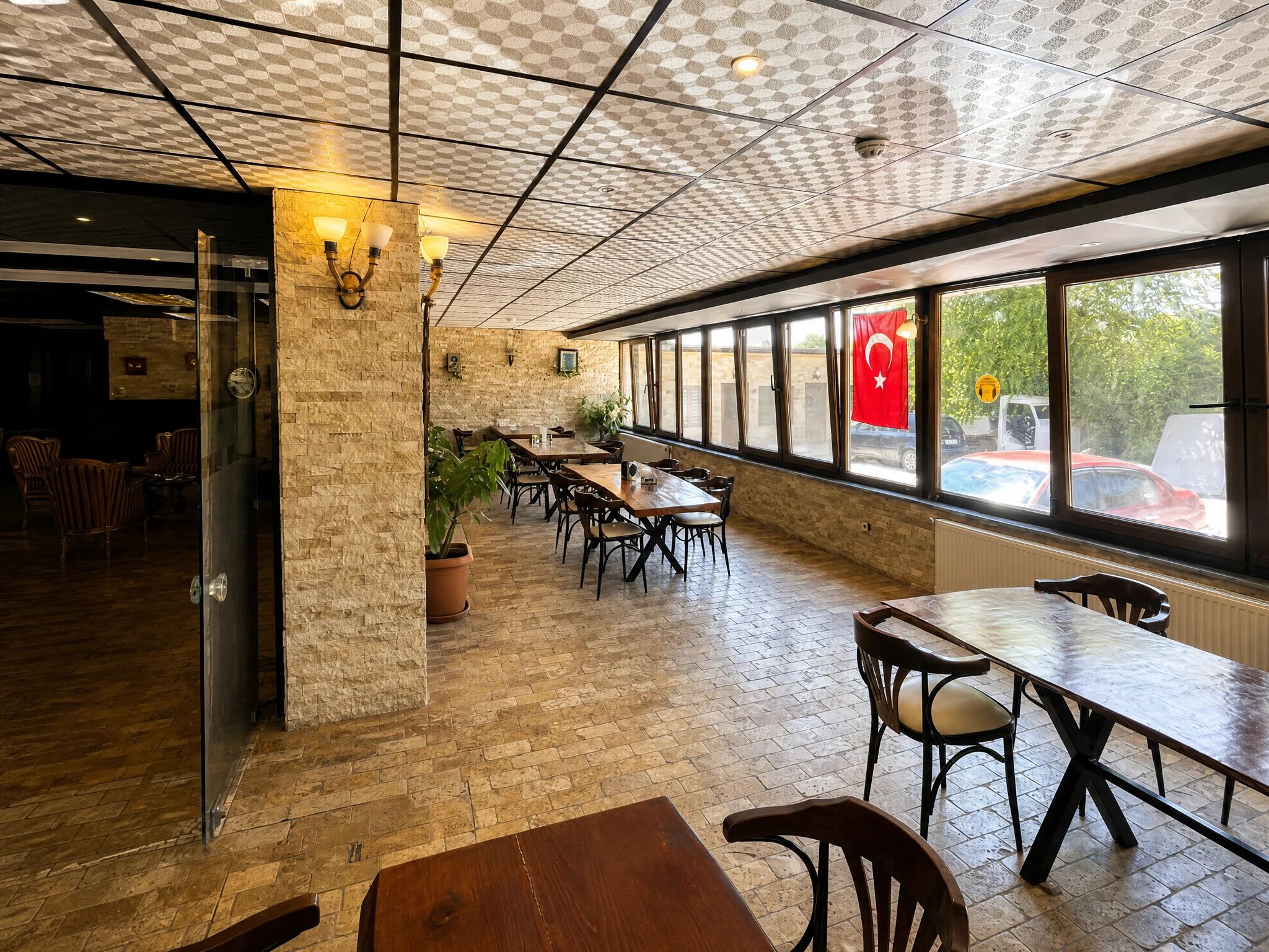 Un comedor interior con paredes de ladrillo, ventanas amplias y un techo con diseño geométrico.